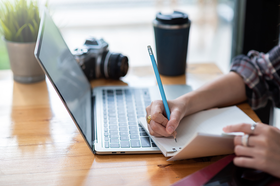 Mujer anotando las características que debe tener un blog antes de comenzar a crearlo.